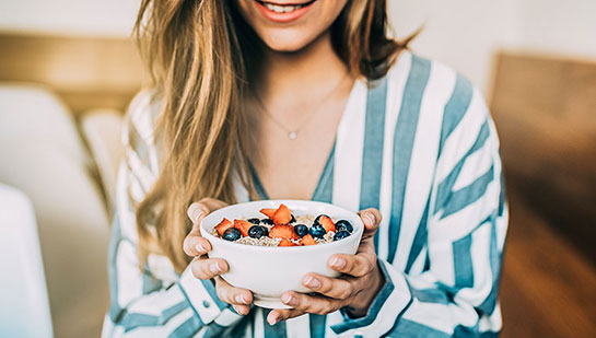 Woman eating a healthy cereal after receiving diet guidance from Oakland chiropractor