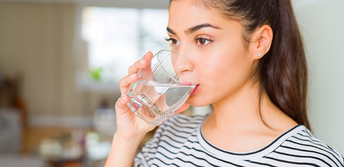 Woman drinking water to be healthy under the guidance of Oakland chiropractor