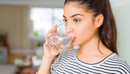 Woman drinking water to be healthy under the guidance of Oakland chiropractor