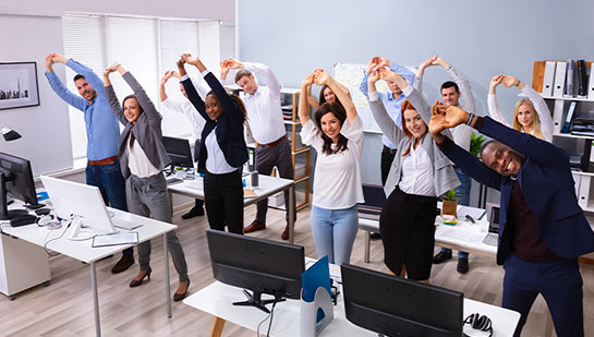 Office team stretching together under guidance of Oakland chiropractor